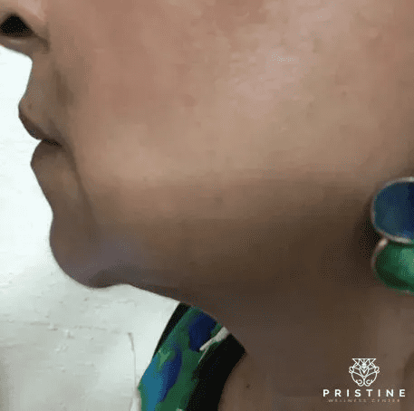 A woman with green earrings and blue necklace.