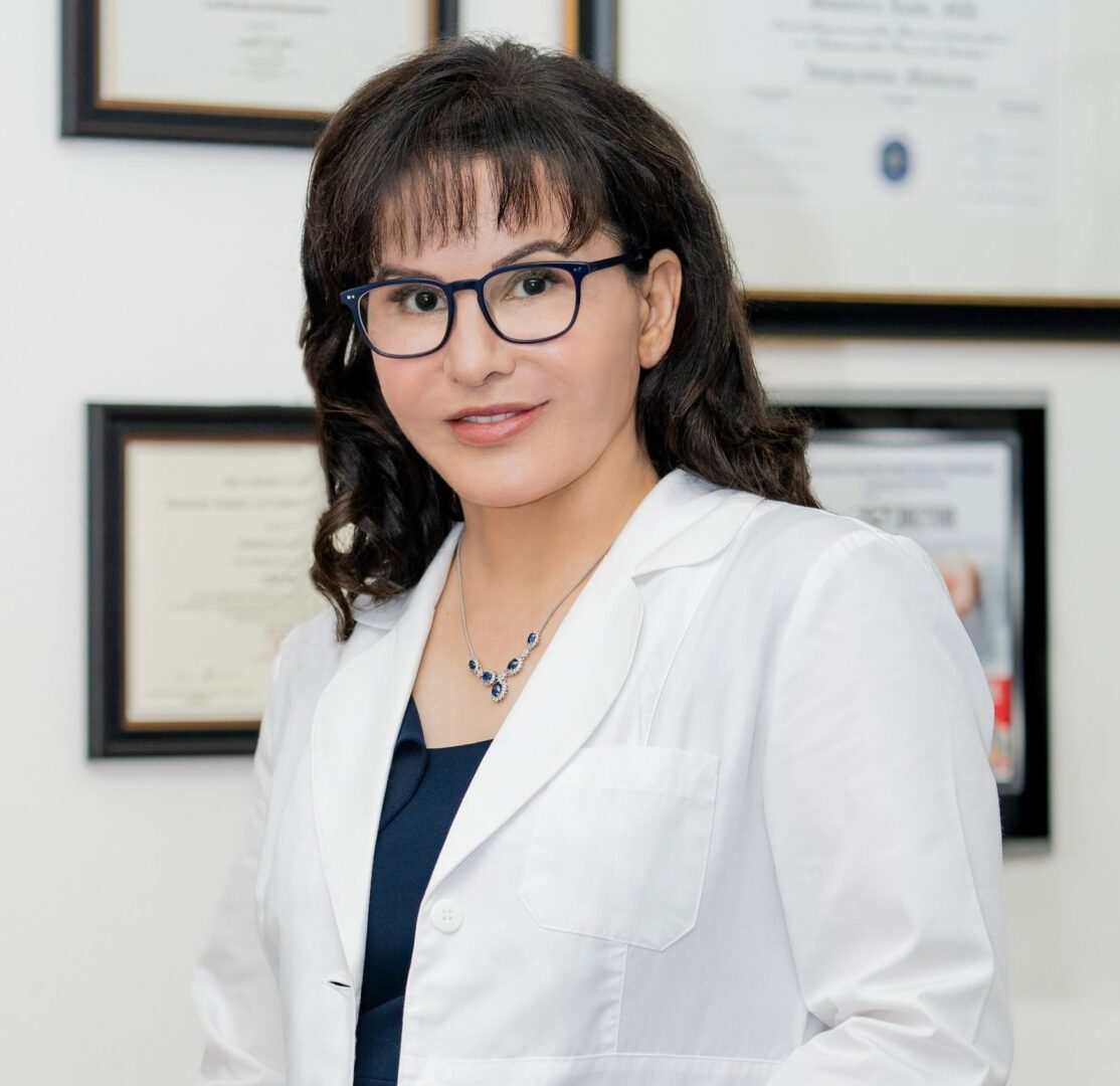 A woman in a lab coat is posing for a photo.